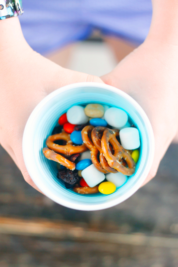 A cup full of trail mix including pretzels, chocolate candies, marshmallows, nuts and more!