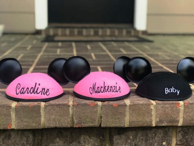 Two pink Mickey ears hats and one black Mickey ears hat announcing a new baby is coming.
