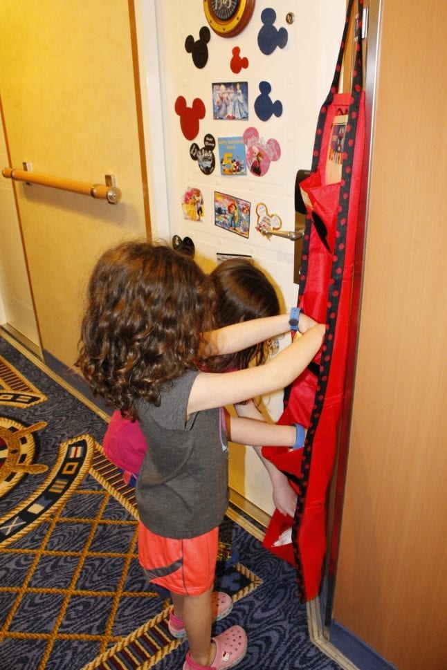 Twin girls putting gifts in a fish extender hanger on the Disney Magic.